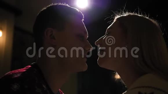 一对相爱的夫妇在黑暗中的剪影在他们亲吻的聚光灯下视频的预览图