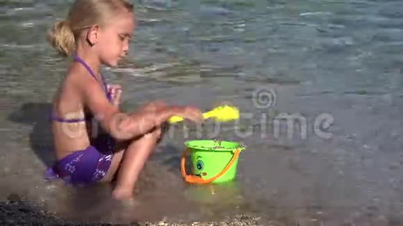 4K孩子在沙滩上玩耍孩子在海滨的波浪中玩耍女孩在海岸上建造城堡湾视频的预览图