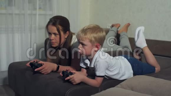 有趣的妈妈和一个小孩一起玩电子游戏他们躺在沙发上视频的预览图