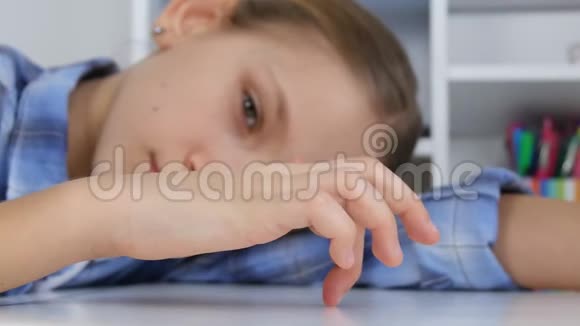 悲伤的孩子无聊的女孩在桌子上玩手指穿着不快乐的孩子不学习视频的预览图