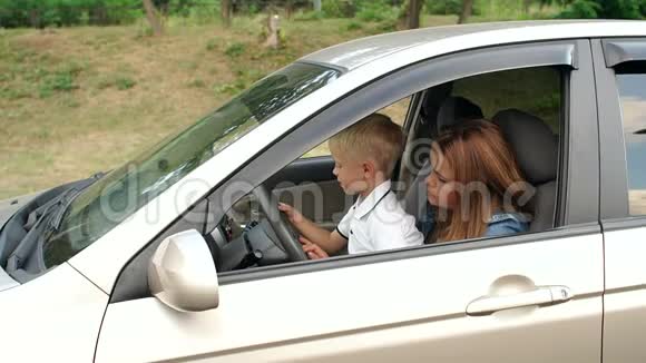 一个小男孩和他的母亲坐在汽车的车轮上打开雨刷视频的预览图