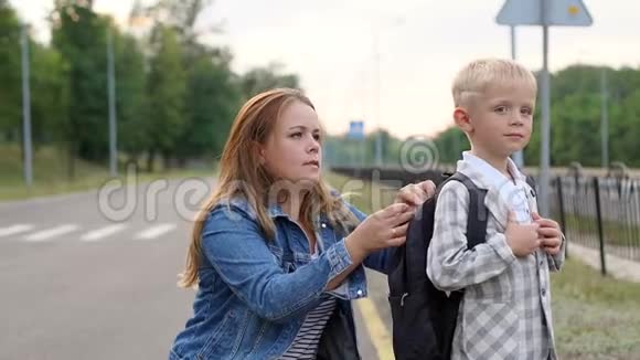 一位有爱心的母亲在放学前调整他背上的背包视频的预览图