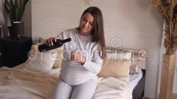 未来妈妈在家里把酒从瓶子里倒进玻璃杯里特写镜头视频的预览图