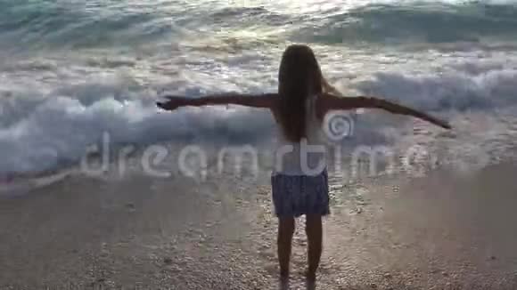 在日落的沙滩上玩耍看海浪的孩子在沙滩上快乐的女孩视频的预览图