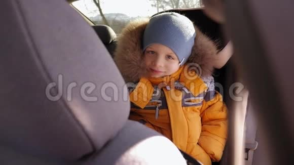冬天的一个小男孩坐在车里的座位上孩子挥动他的手视频的预览图