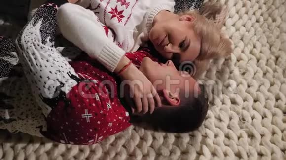 一对夫妇穿着圣诞毛衣躺在地板上的针织毛毯在家里视频的预览图