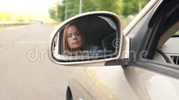 年轻女子在车的侧镜里的倒影她把头发弄直了视频的预览图