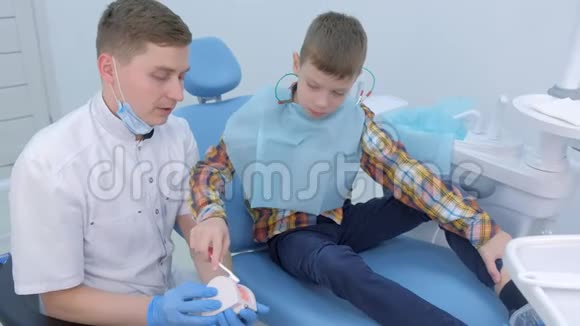 牙医教小男孩如何使用玩具下巴模型清洁牙齿视频的预览图