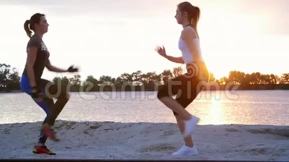 美丽苗条的年轻女性从事健身跳跃表演力量练习黎明时分在沙石场视频的预览图