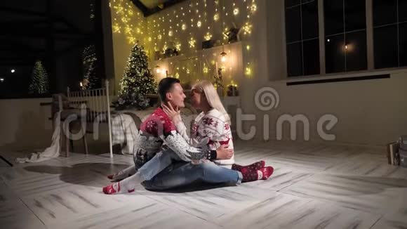 年轻夫妇坐在圣诞树前的地板上拥抱视频的预览图