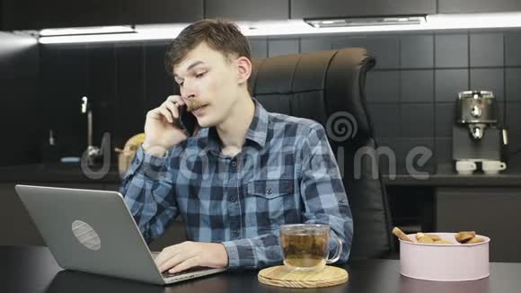 从家里打友好电话的人年轻的男性自由职业者在家里工作笔记本电脑在智能手机上交谈巴士视频的预览图
