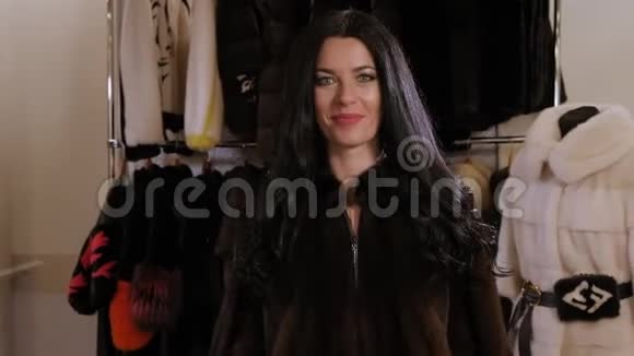 一个留着长发的豪华女孩在一家女装商店试穿一件毛皮大衣视频的预览图