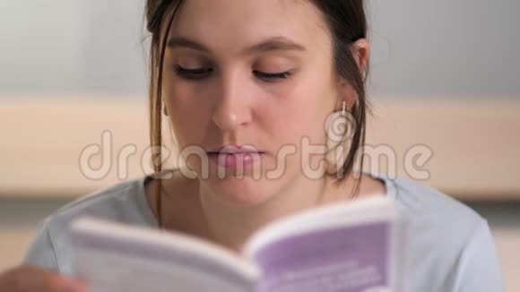 女孩在看书年轻迷人的白种人女人晚上坐在床上睡觉前仔细地看书视频的预览图
