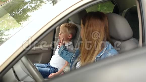 一个女人带着一个孩子在汽车前座的肖像孩子吃糖果视频的预览图