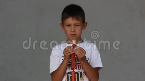 一个在灰色背景下吃香肠的男孩膨胀香肠咬视频的预览图