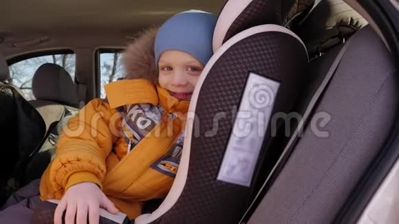 可爱可爱的学龄前小男孩坐在车里穿着冬天的衣服视频的预览图