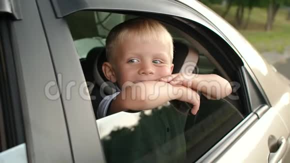一个小男孩坐在汽车的后座上他望着窗外微笑视频的预览图