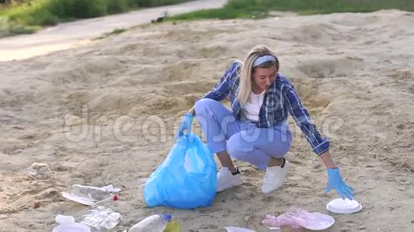一个女志愿者在海滩上捡垃圾一个女孩正在打扫海滩视频的预览图