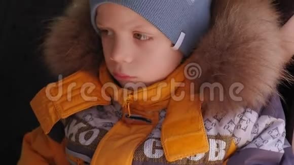 特写一个愁眉苦脸的小男孩穿着黄色的冬天夹克在车里视频的预览图