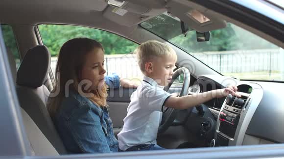 男孩和母亲坐在驾驶座他按下按钮视频的预览图