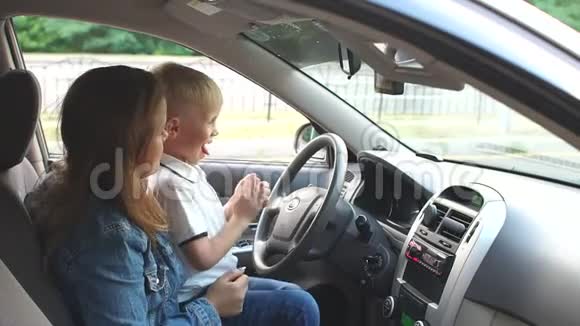 妈妈带着一个儿子在车里玩他们坐在方向盘后面跳舞视频的预览图