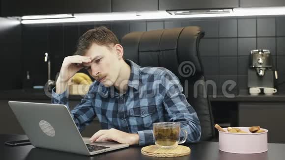 担心男性自由职业者头痛在家工作笔记本电脑在厨房做笔记本的人很不高兴不快乐的人视频的预览图