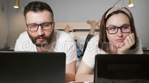 自由家庭在家工作的概念男人和女人躺在卧室的床上同时在上面打字视频的预览图