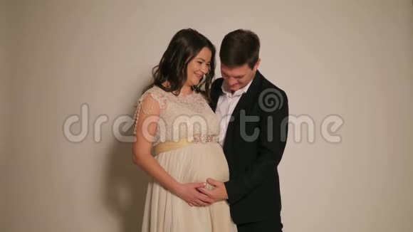 丈夫在白色背景下拥抱怀孕的妻子视频的预览图