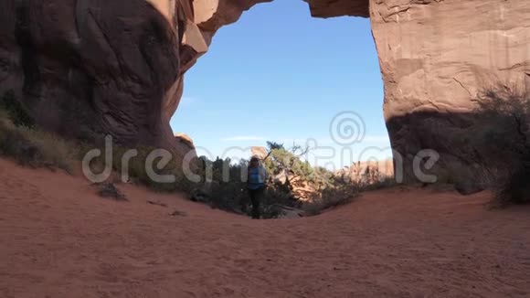 在沙漠徒步旅行者以拱门形式形成岩石的背景视频的预览图