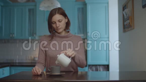 30多岁的年轻女性将牛奶从锅里倒入咖啡杯中女人拿着杯咖啡闻着咖啡享受视频的预览图