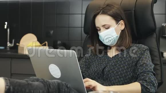 家庭笔记本电脑工作后自由职业者脱下保护性医疗面罩年轻的黑发妇女戴医用面罩工作视频的预览图