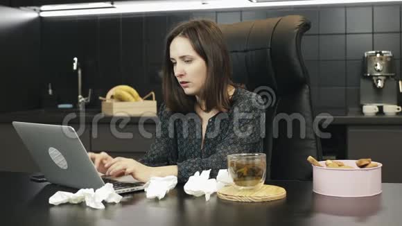 生病的妇女感冒咳嗽和打喷嚏在家里的办公室工作生病的女性在家里用笔记本电脑工作坏女孩视频的预览图