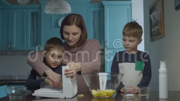 家庭烹饪薯片在切片机上母亲和儿子们做土豆片把它放进玻璃碗里幸福的家庭视频的预览图