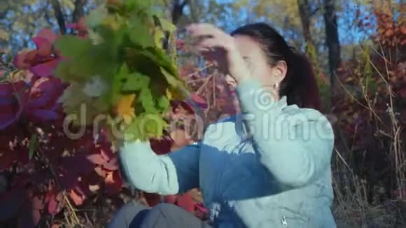 美丽的女人放在森林中秋叶树的头上视频的预览图