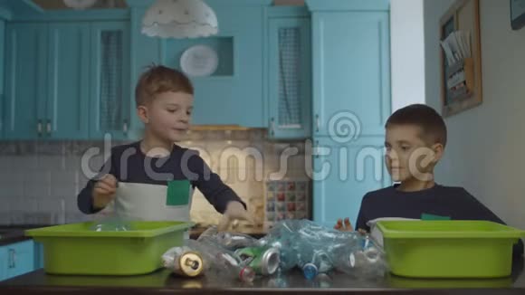 两个男孩把家里的垃圾分类以回收塑料和锡环保家庭减少塑料消耗视频的预览图