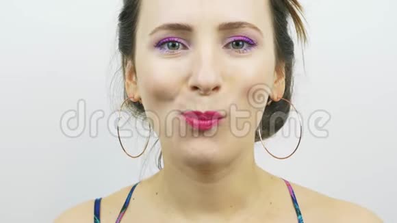 迷人的年轻女人在镜头前咀嚼白色背景下镜头咀嚼粉色妆容的快乐女孩画像视频的预览图