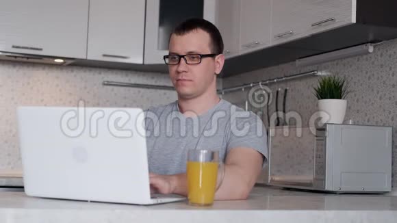 年轻的男性自由职业者在网上工作时使用笔记本电脑看着屏幕微笑着视频的预览图