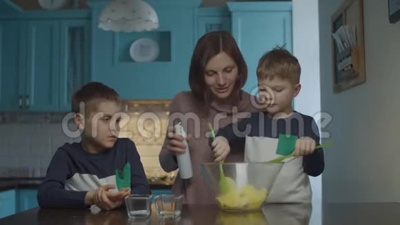 家庭在家煮薯片母亲和儿子把土豆片混合在玻璃碗里加入盐和香料快乐视频的预览图