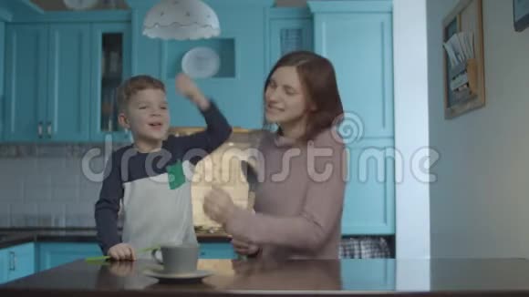快乐的家庭跳舞和唱歌进入厨房就像麦克风在家庭蓝色厨房女人跳舞视频的预览图