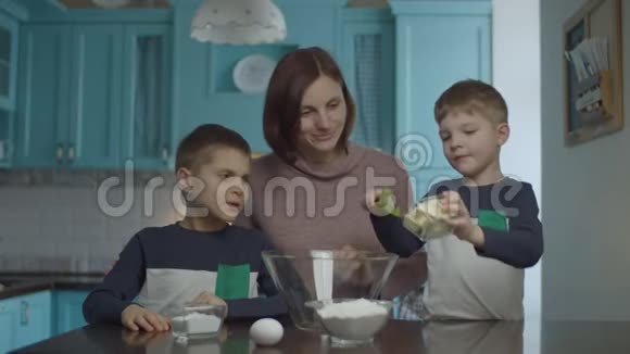 孩子们帮妈妈揉黄油糖鸡蛋和面粉的面团快乐的家庭烹饪饼干和乐趣视频的预览图