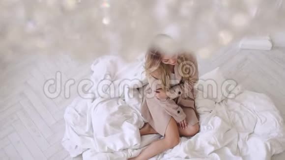 穿着米色外套的女孩模特坐在铺着白色毯子的地板上视频的预览图