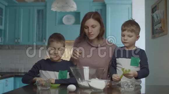 孩子们帮妈妈揉黄油糖鸡蛋和面粉的面团快乐的家庭烹饪饼干和乐趣视频的预览图