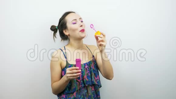 快乐的笑女人吹泡泡微笑迷人的女性嘴唇上涂着粉红色的口红吹着泡泡视频的预览图