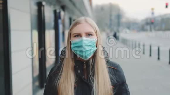 年轻的金发女人在街上戴着保护性医疗面具视频的预览图