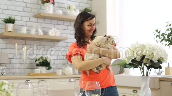 女人手里拿着两只小狗在厨房里视频的预览图