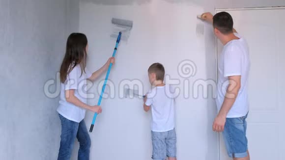 家庭的妈妈爸爸和儿子正在用油漆滚筒用灰色油漆墙壁视频的预览图