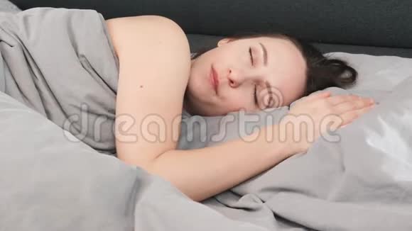 楚楚可怜的女性闭着眼睛躺在床上闭上了眼睛年轻的黑发女人睡在空床上的枕头上可爱的女孩的谎言视频的预览图