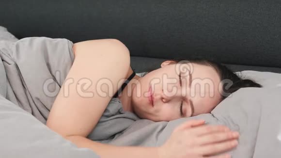 闭上女人的脸闭着眼睛躺在床上年轻迷人的女性独自睡在床上迷人女孩的肖像视频的预览图