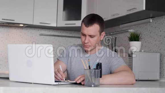 一个年轻人很难在家远距离工作坐在桌子旁时双手背在脑后视频的预览图