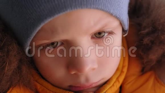 特写一个愁眉苦脸的小男孩穿着黄色的冬天夹克在车里视频的预览图